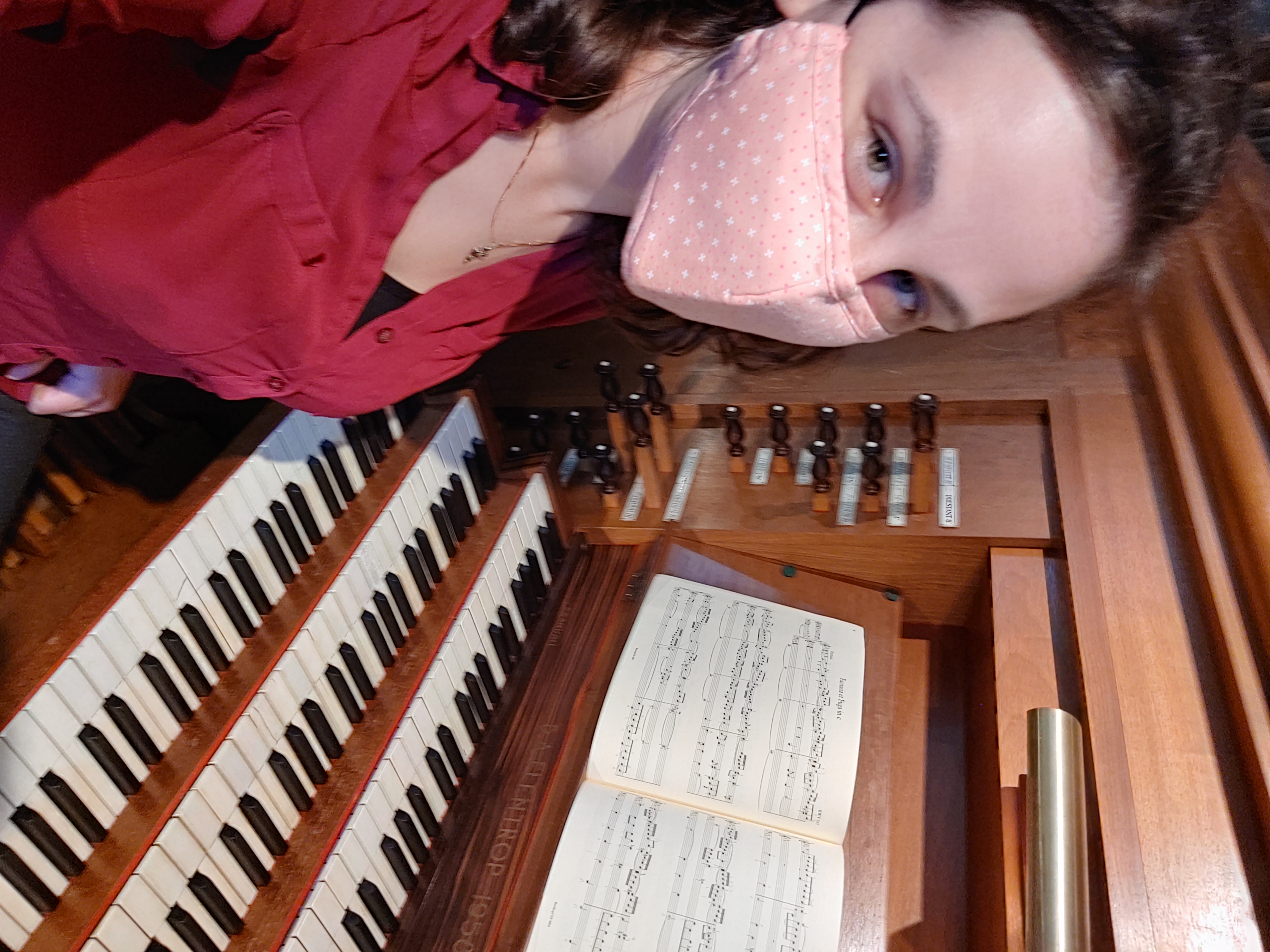 Me wearing a pink mask sitting at the organ console in Busch Hall at Harvard.